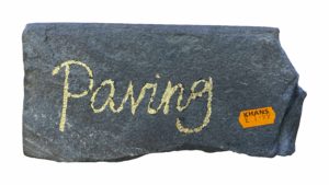 An image of a dark grey slate / rock with the word paving on it. An orange price sticker has been stuck on it. 