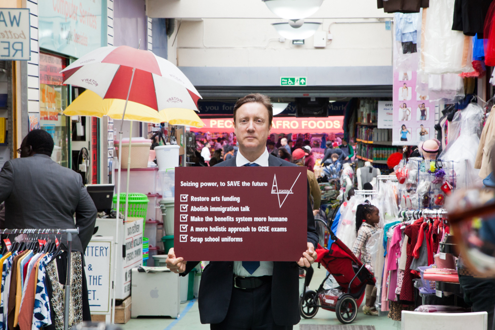 <p>Art Assassins’ political manifesto held by David Cameron lookalike Bentley Browning, May 2015. Photo: Manuela Barczewski.</p>
