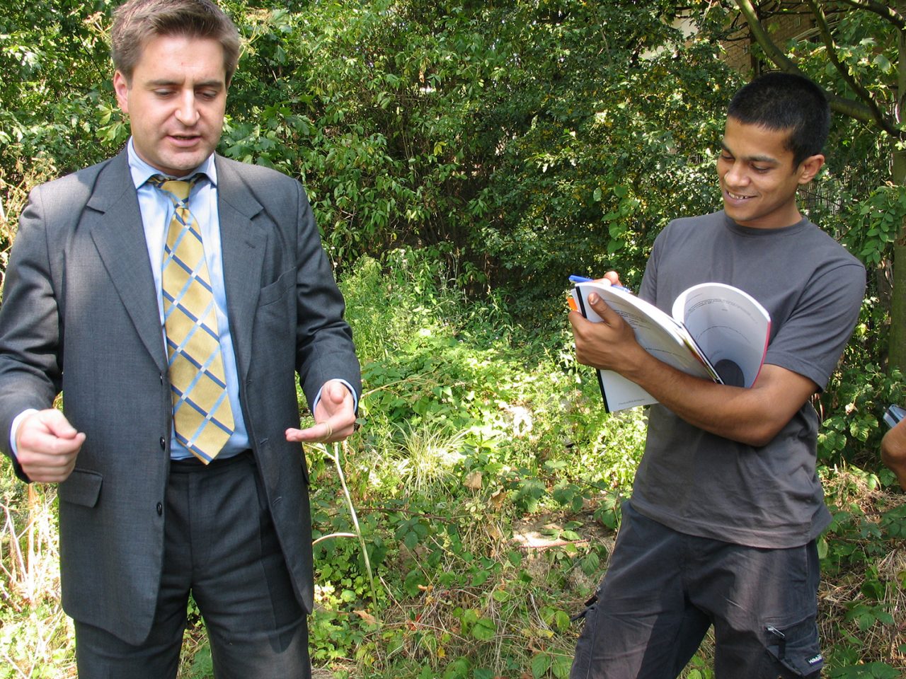 Image of the artist giving a stranger a plot of land as a gift through a paper contract in Burgess Park.