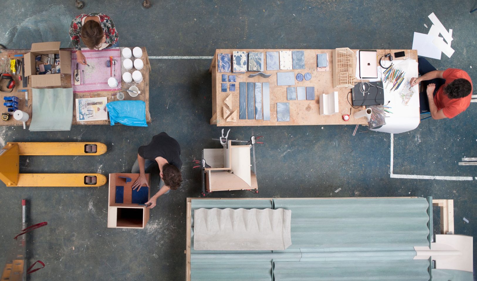 View of three people working at tables in a studio