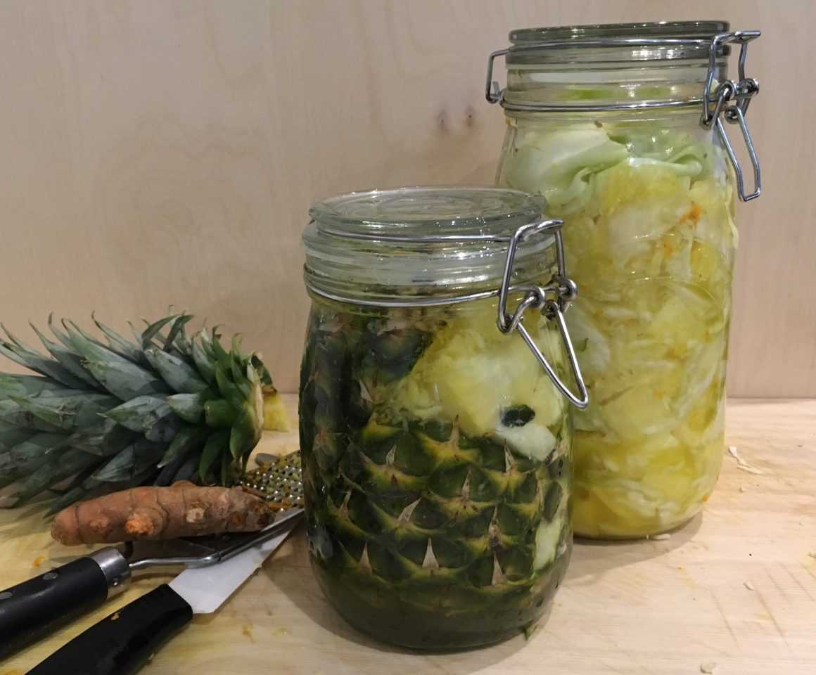 Two glass jars containing fruits and vegetables in pickling liquid