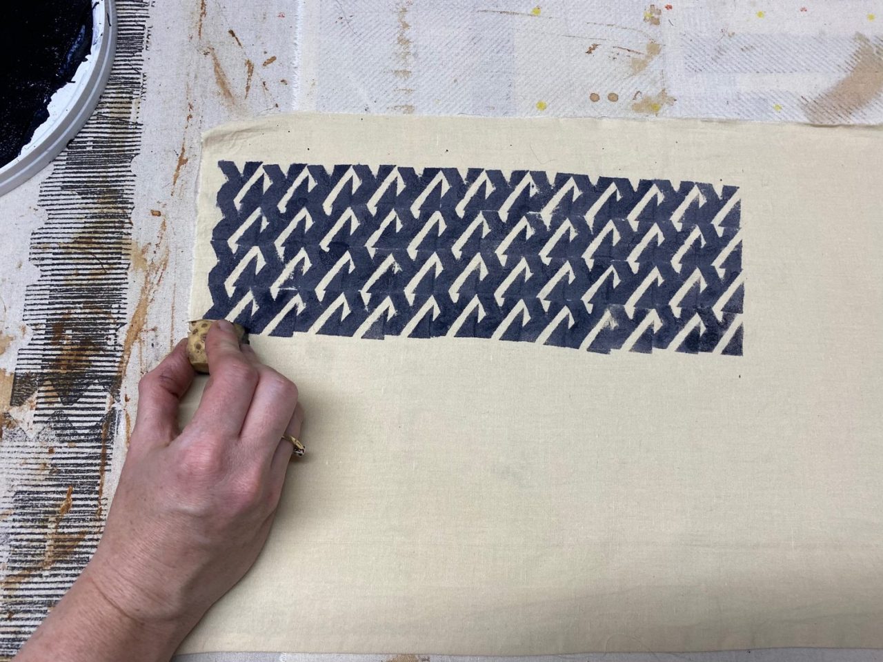 A hand using a block to create a print on fabric