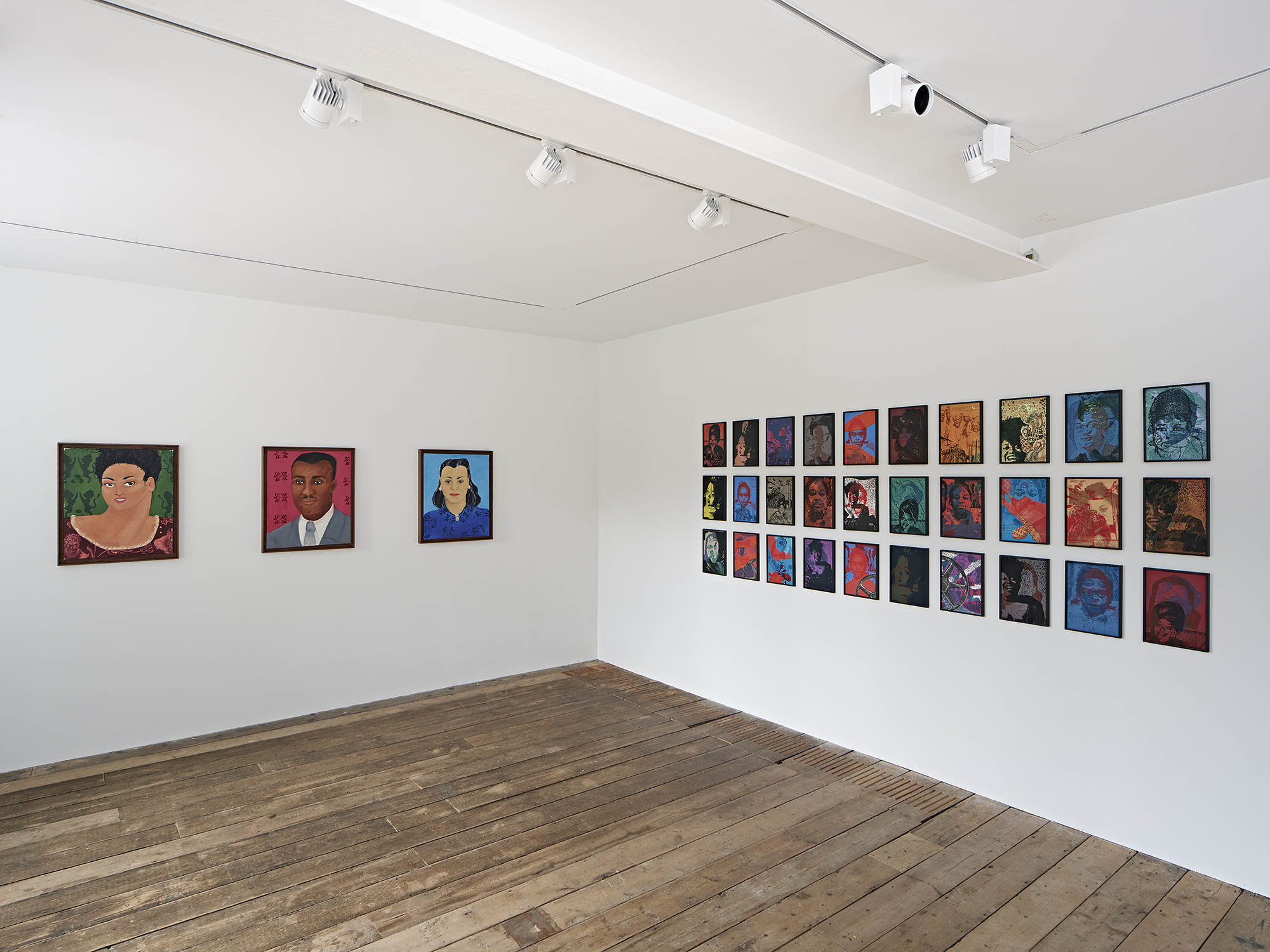 A photo of a gallery space with three paintings hung on the left-hand side of the wall and 30 different small-sized paintings hung on the right-hand side of the wall.
