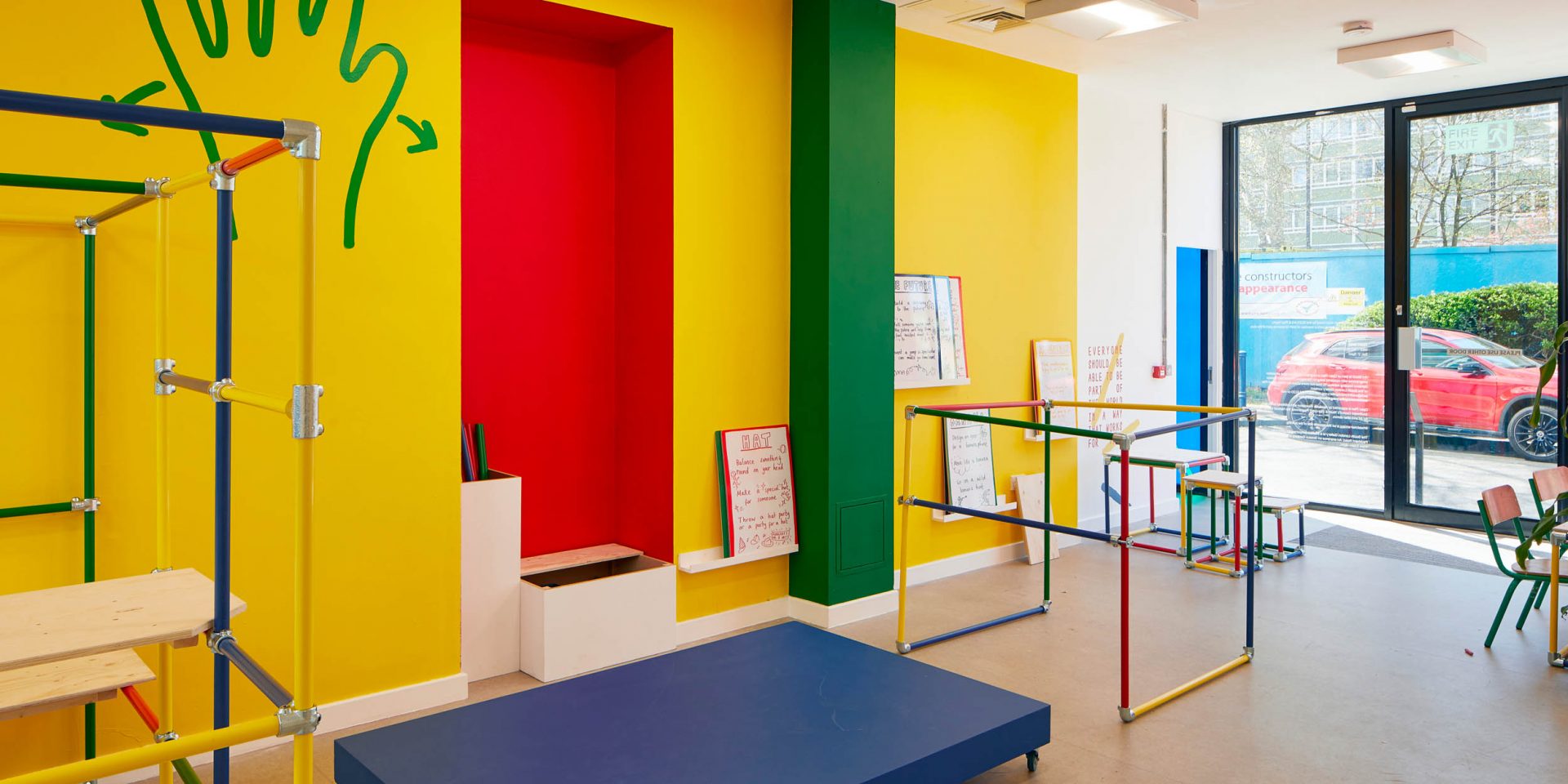 Art Block with a brightly coloured yellow wall, a brightly coloured wood modular structure and a green hand painted onto the wall