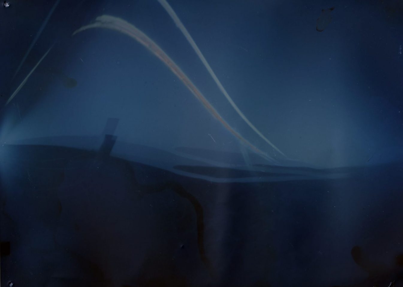 An example of solargraph photography, showing patterns of light on a blue background
