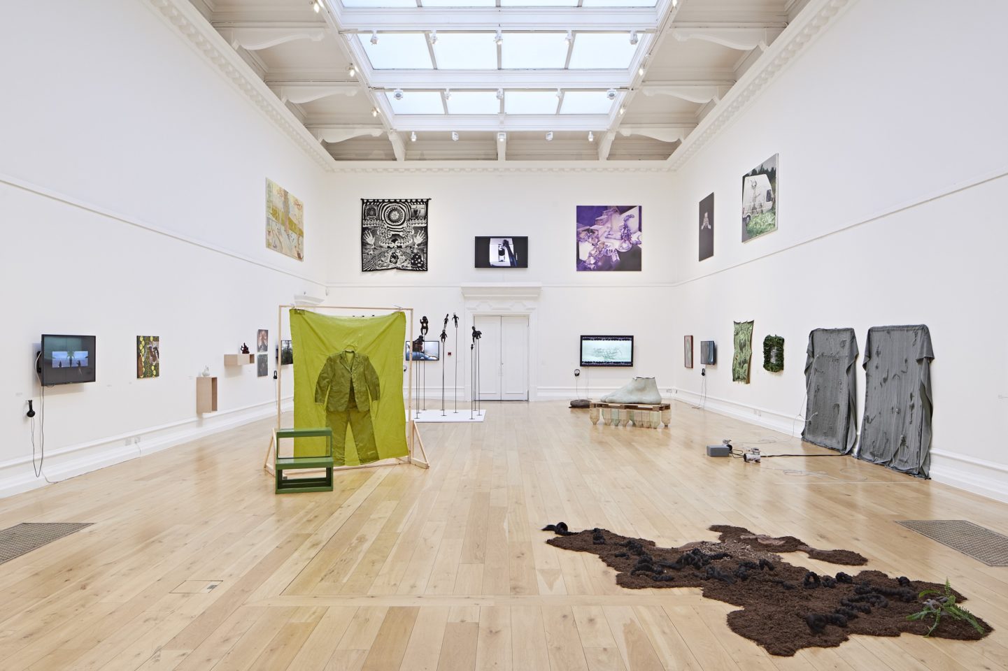 A photo of a large gallery space with many art installations around the room and the walls.