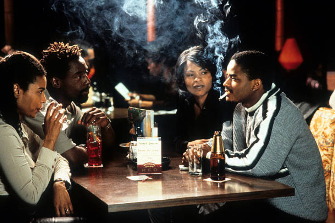 Love Jones film still, four Black people sit around a bar table drinking and smoking