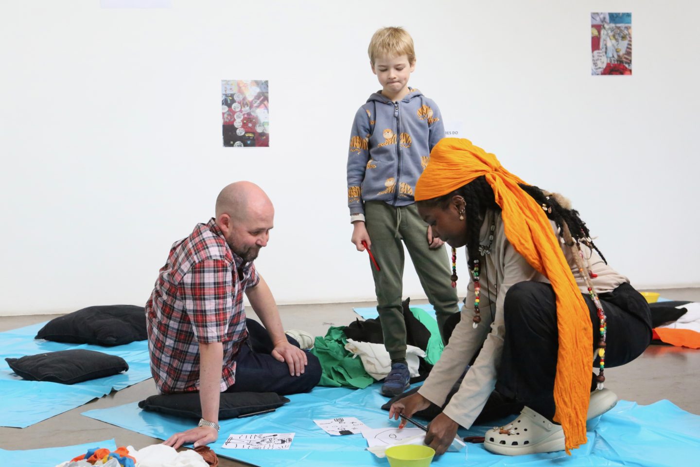 An artist teaches creative activities to a young boy and man.