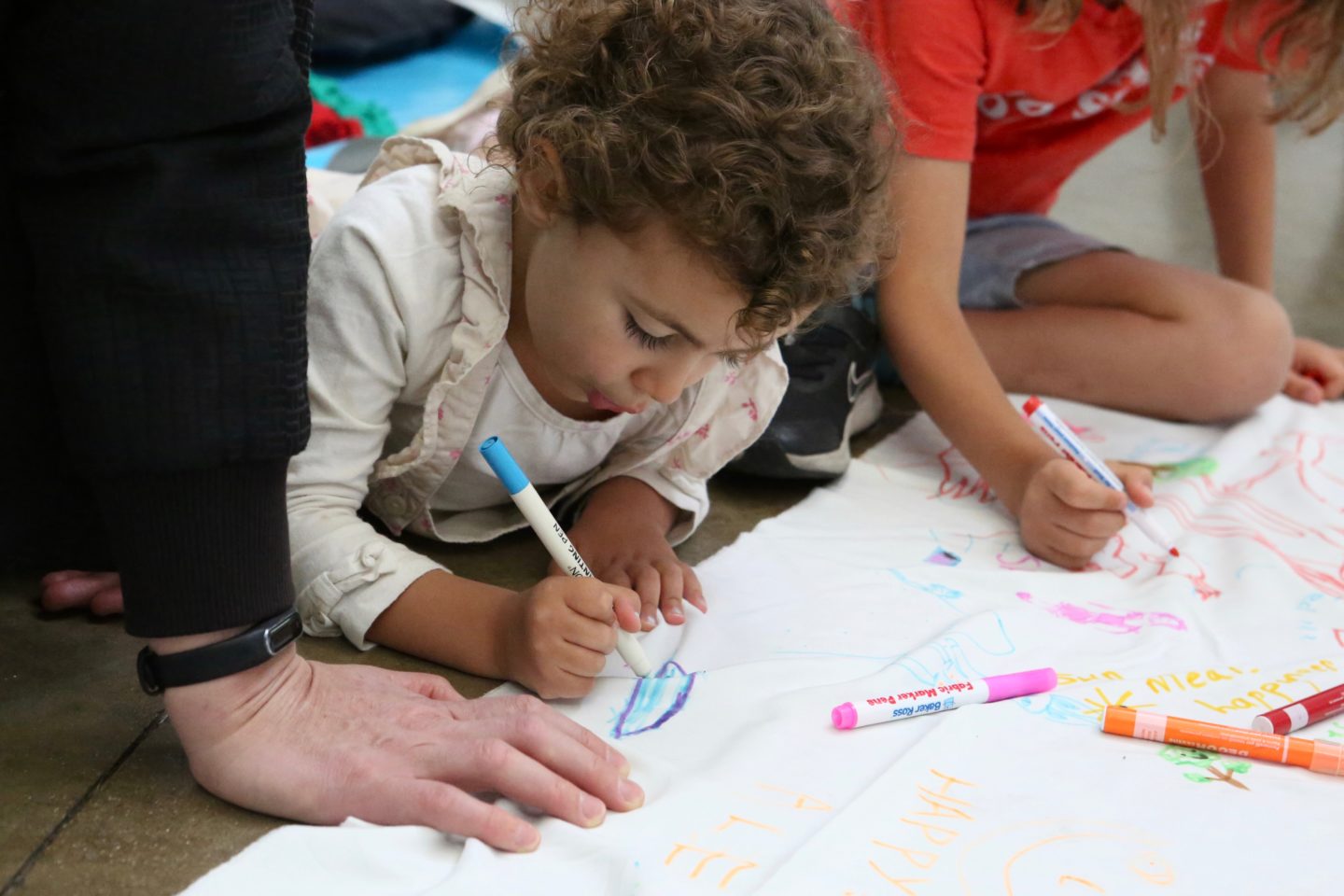 An image of children drawing on fabric