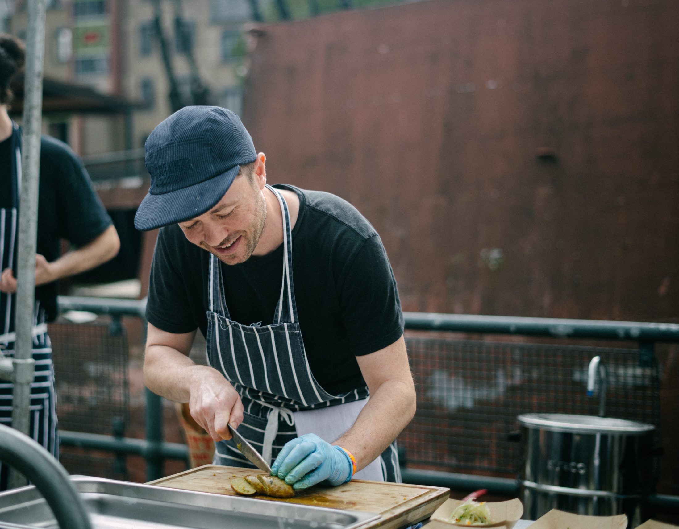 A chef wearing an apron chopping food on a wooden chopping board
