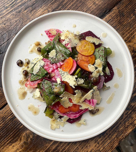 A plate of fresh salad with carrots, beetroot and green leaves