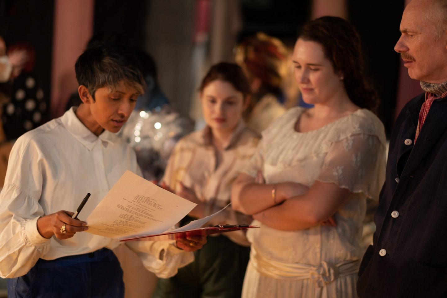 Filmmaker Michelle Williams Gamaker on the set of her film, Thieves. She holds a script and is talking to three actors and crew members.