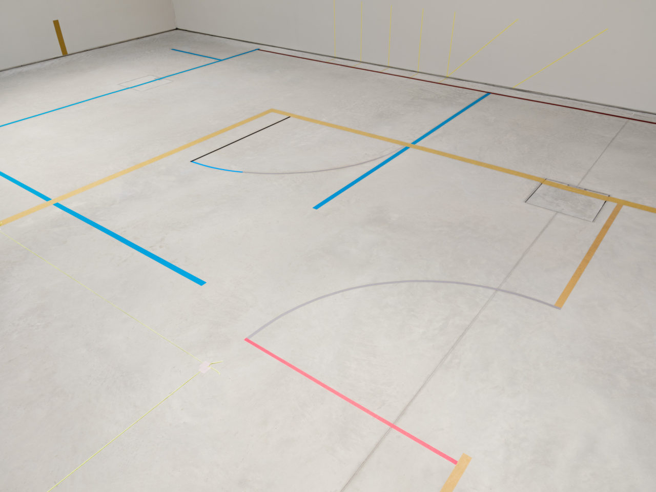 Colourful lines on a grey floor in a gallery space.