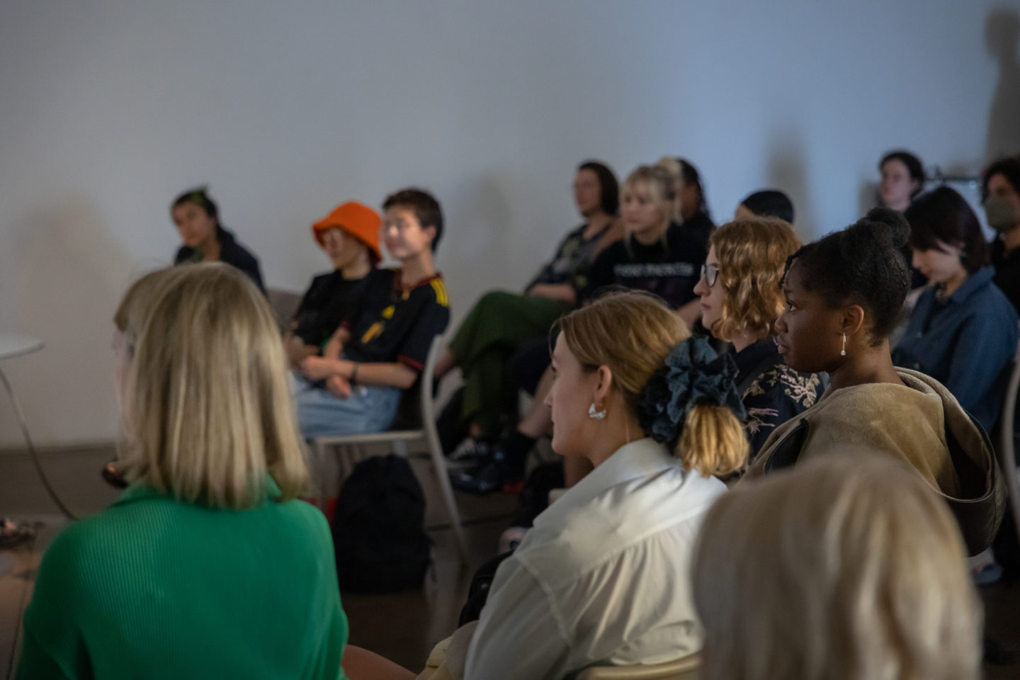 People sit at a panel discussion. They are all facing forward towards the speakers.