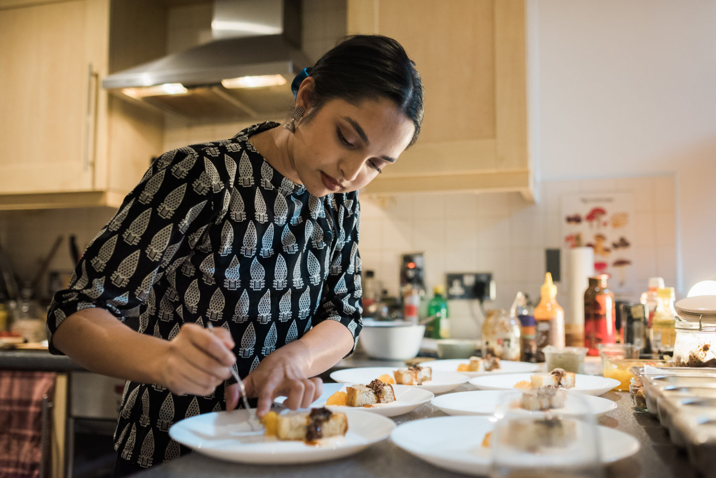 A chef in a kitchen plating up food.