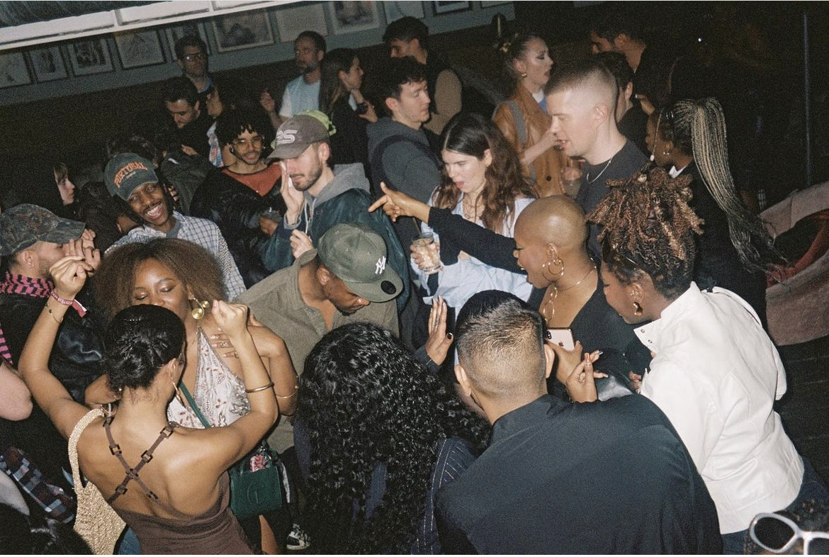 Lots of people at an evening event dancing, talking and smiling.