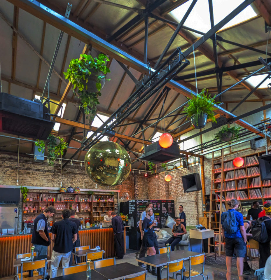 A busy, bright bar with people standing around having drinks.