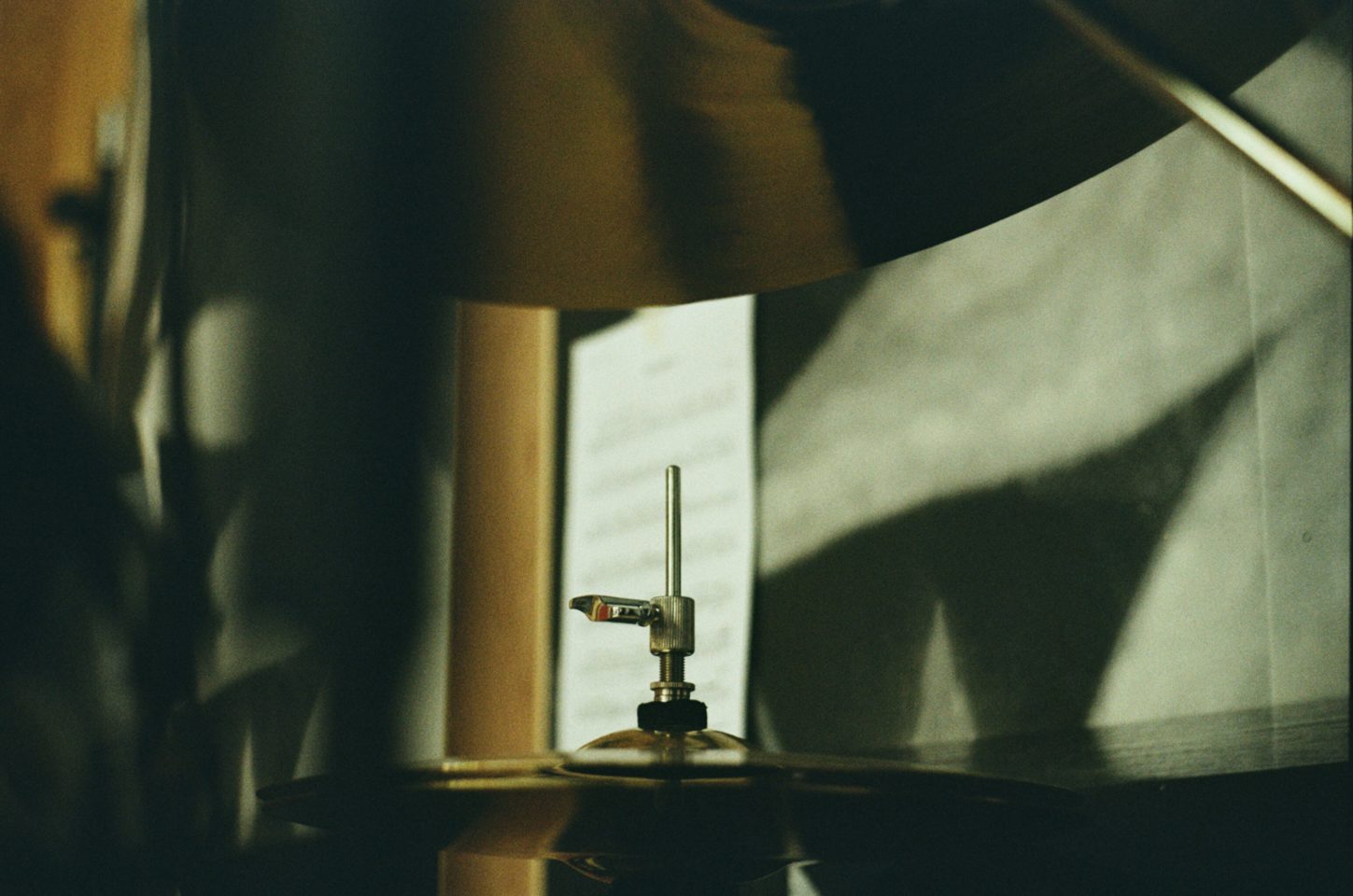 A dark room with lots of shadows. A symbols from a drum kit is in frame.