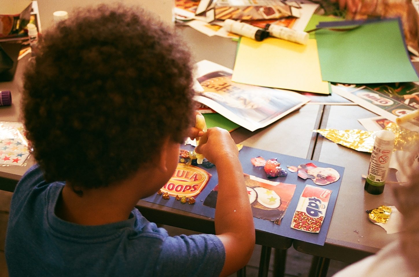 A child makes a colourful collage at a table