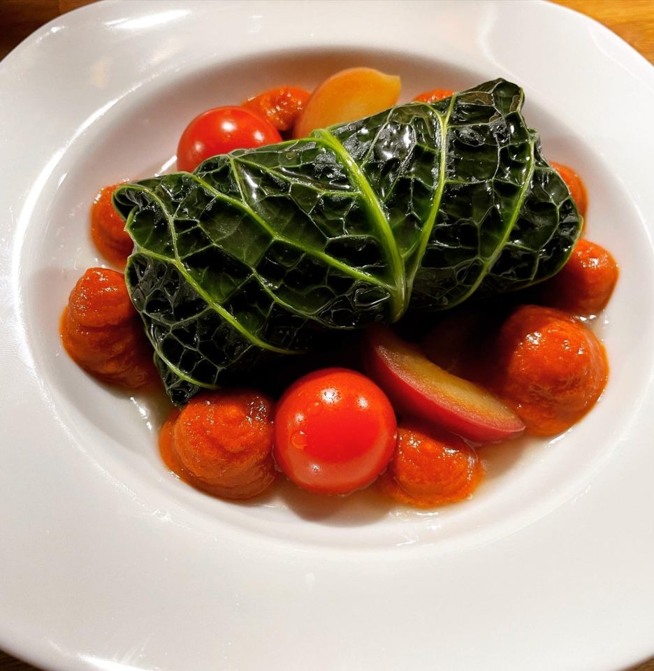 A cabbage leaf and tomatoes on a white plate.