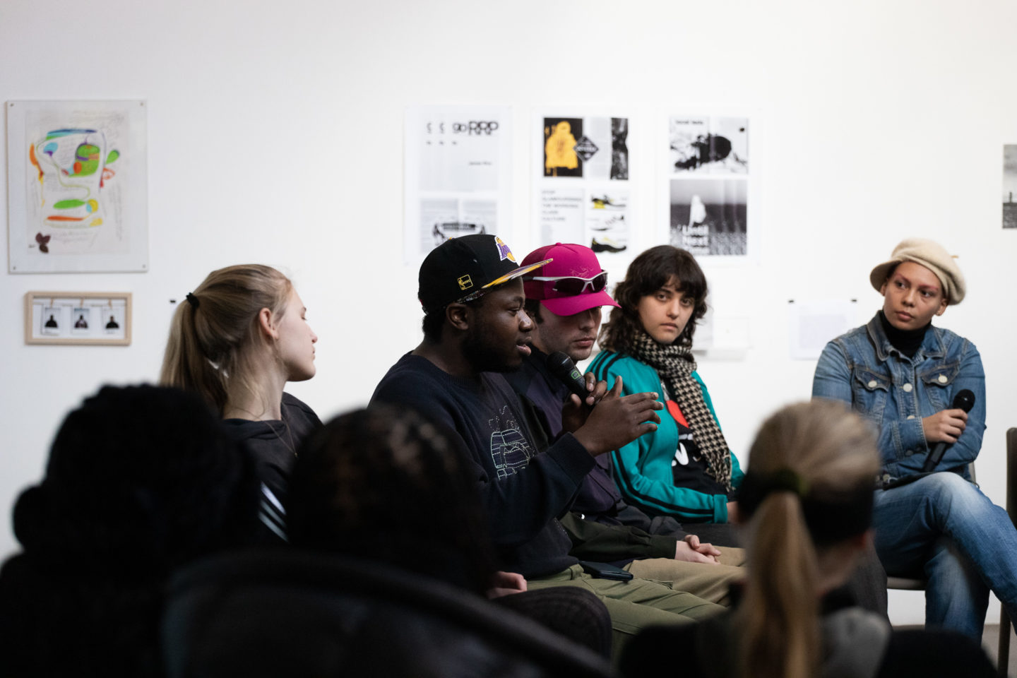 A group of young people speaking on a panel in an art gallery.