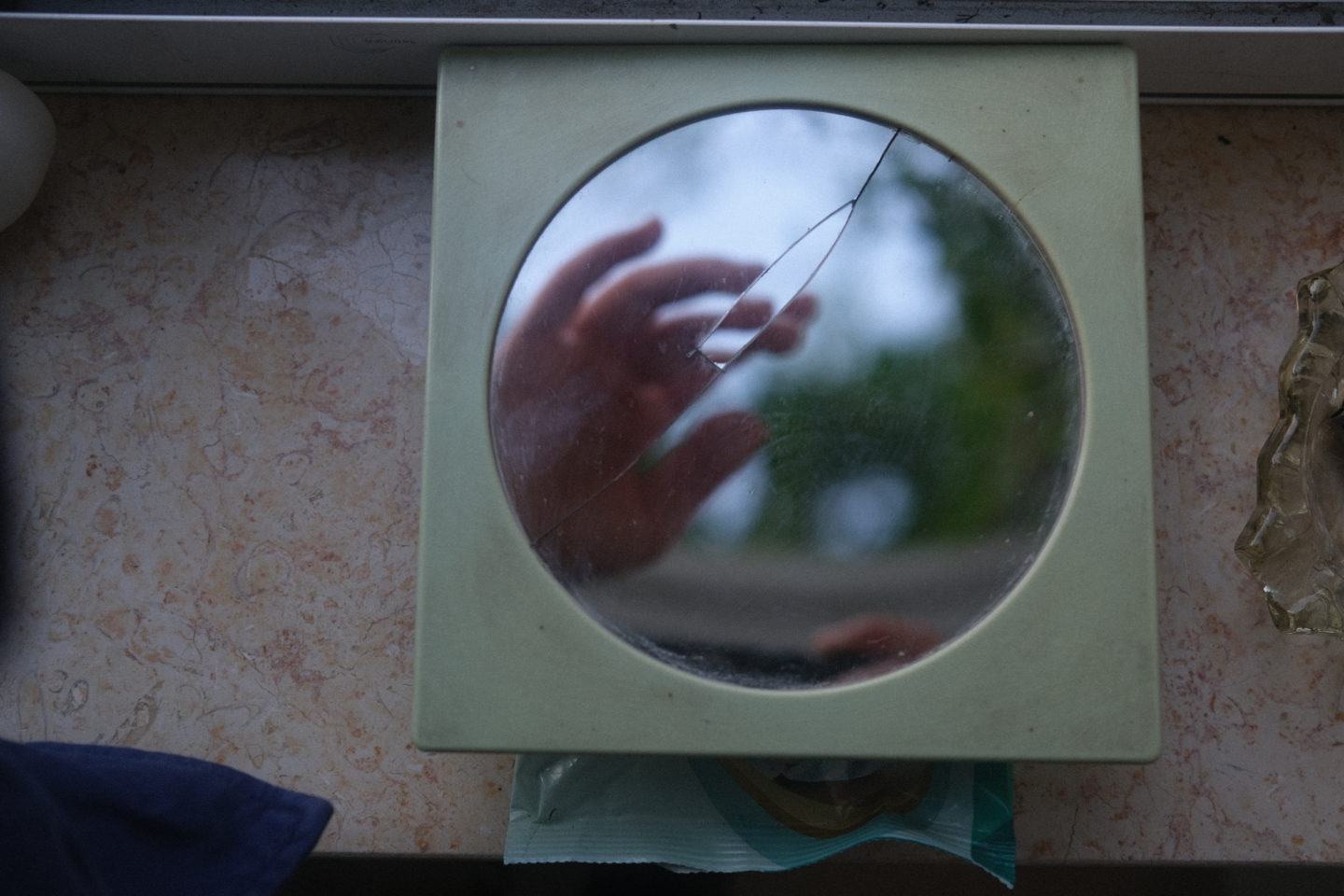 A cracked mirror with a hand reflected in it
