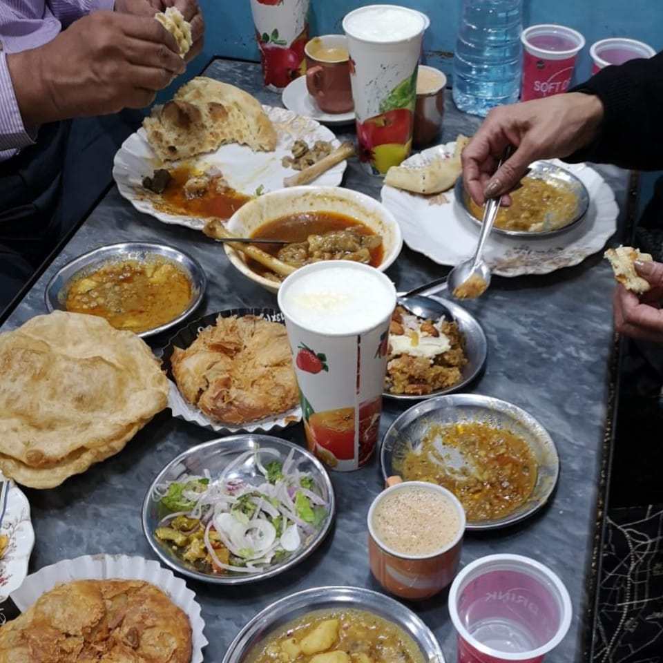 Lots of food on a table with people helping themselves.