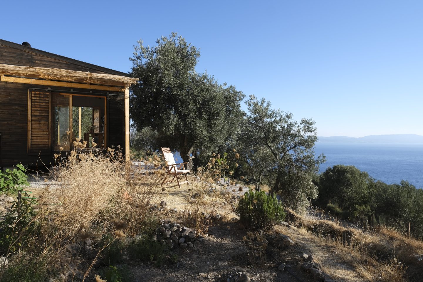 A photo of a house overlooking the sea with a blue sky in the background.