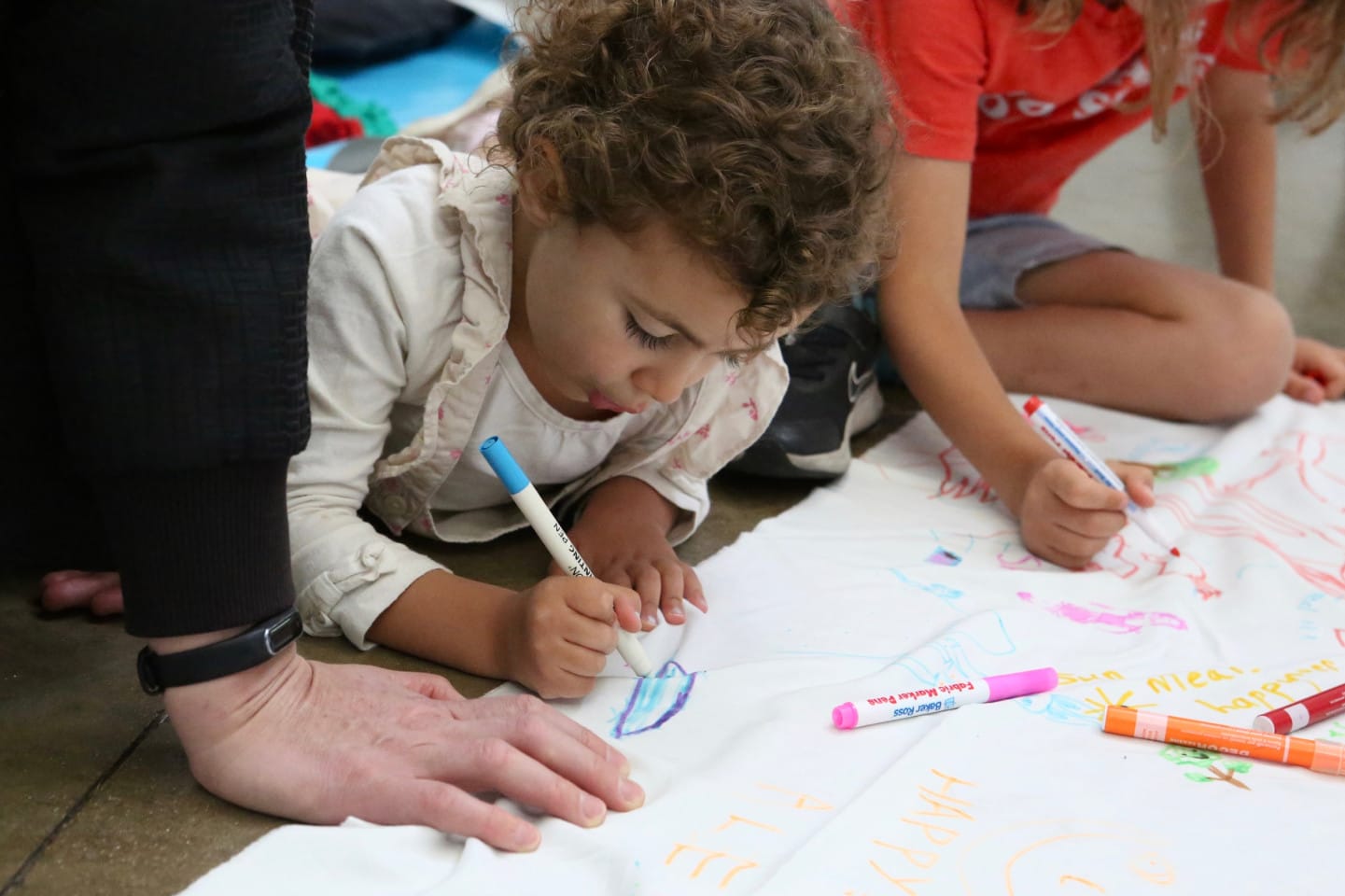 A young child draws on a large piece of paper at a family workshop.