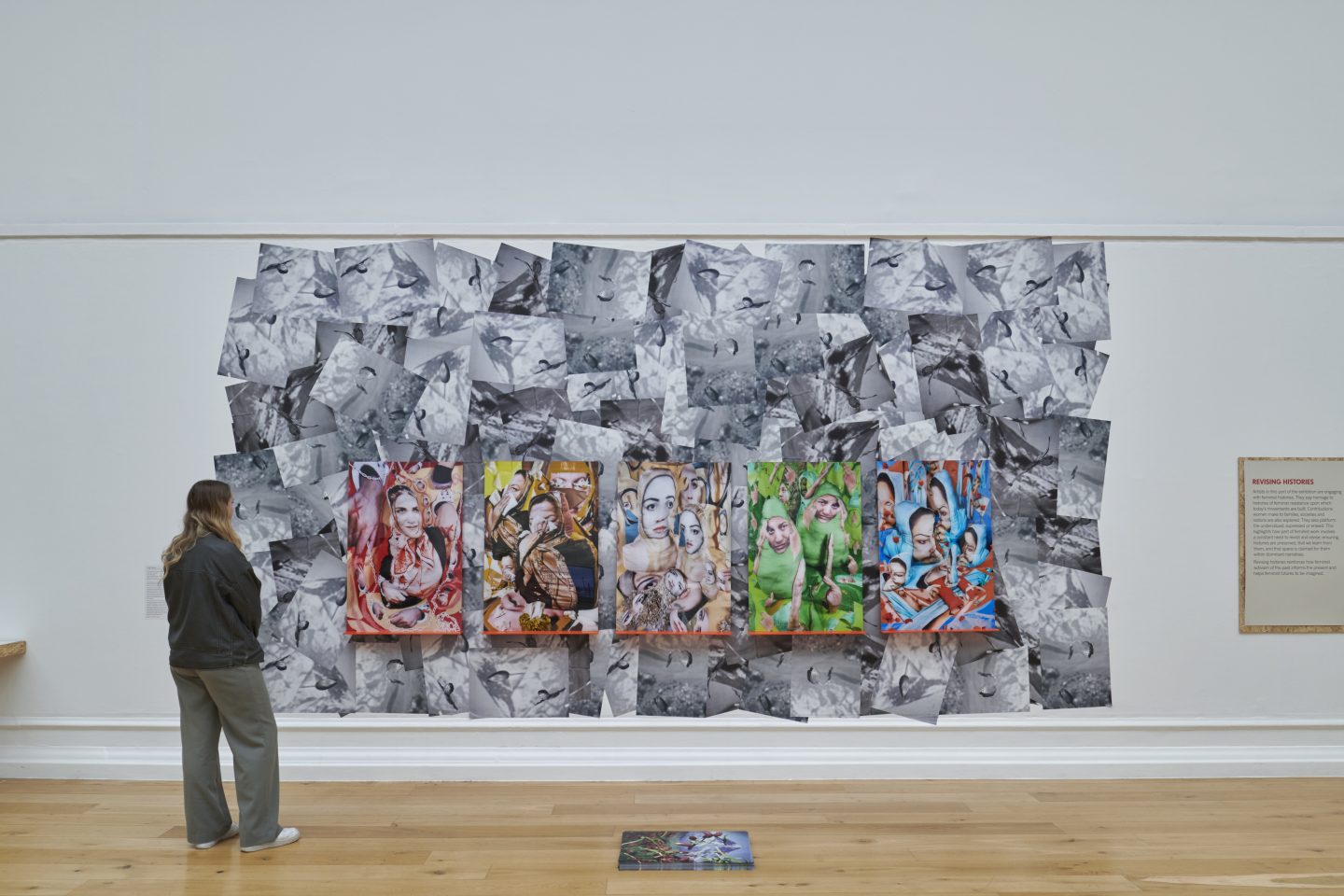 A person stands in a bright art gallery looking at art on a wall.