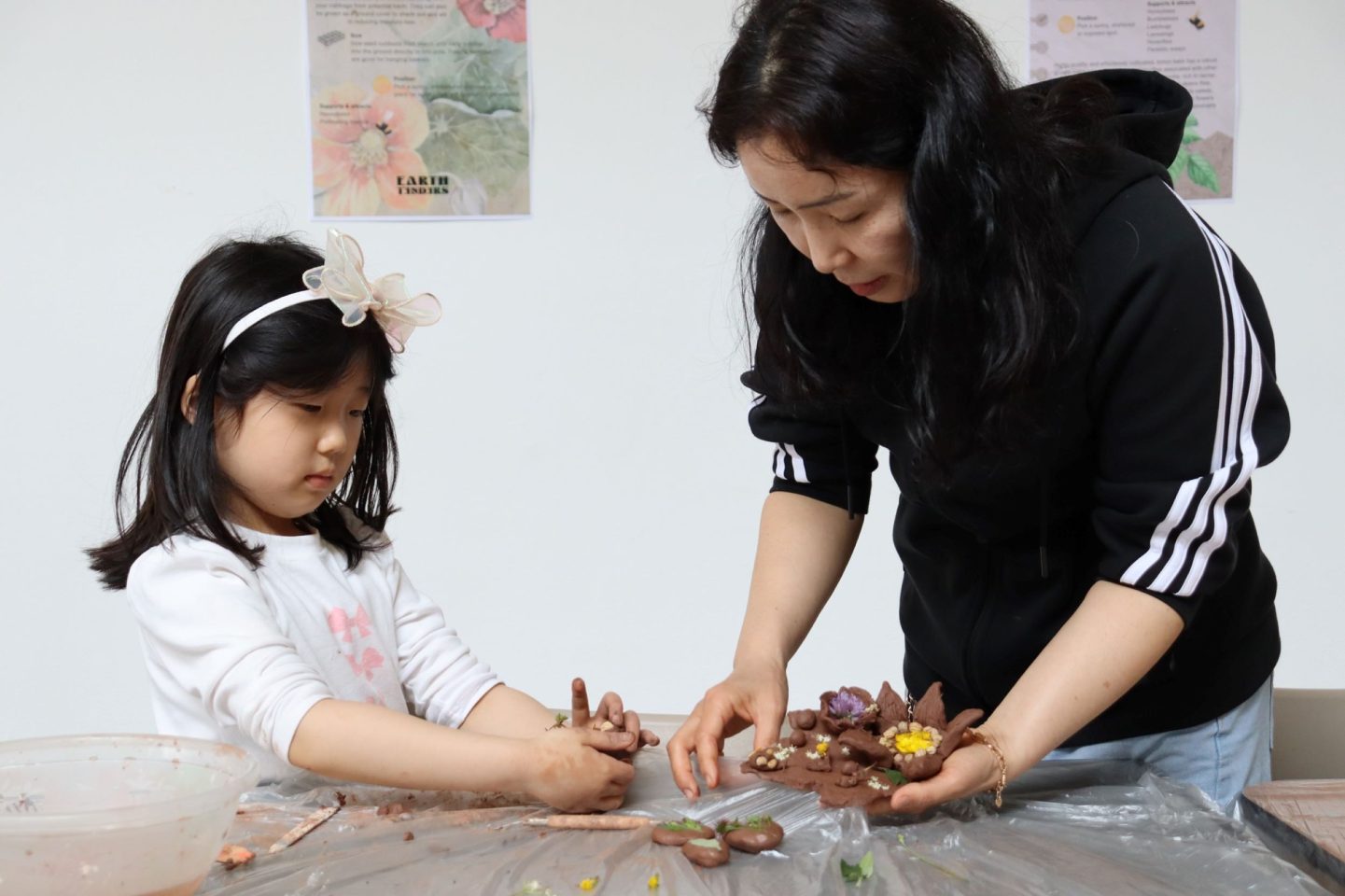 Clay models being sculpted by a child and adult.