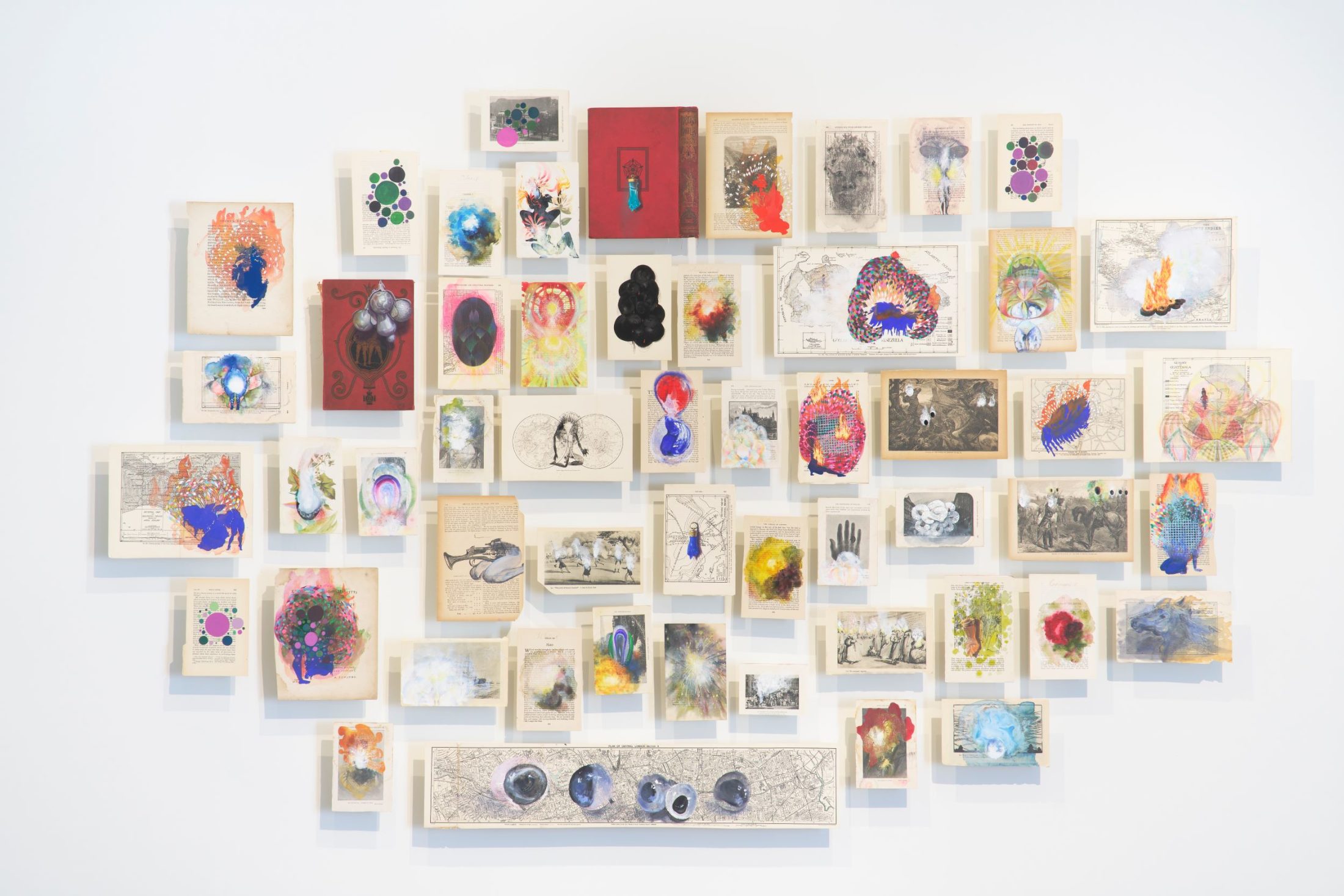 A constellation of book pages with different symbols painted on them in an array of colours