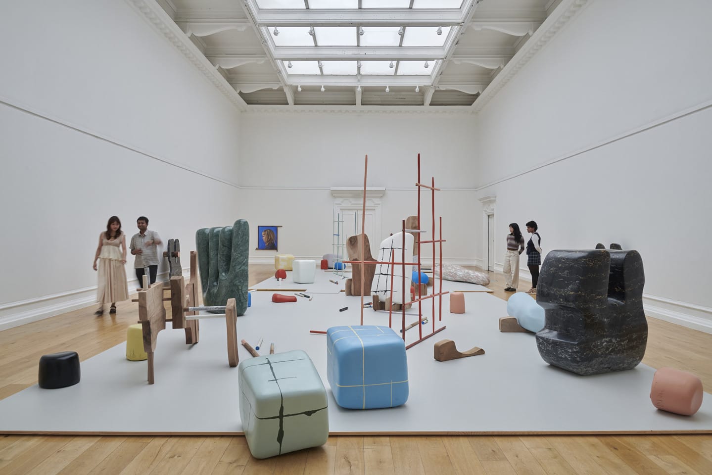 People walk around a large art gallery. They are looking at abstract sculptures and engaging with the art.