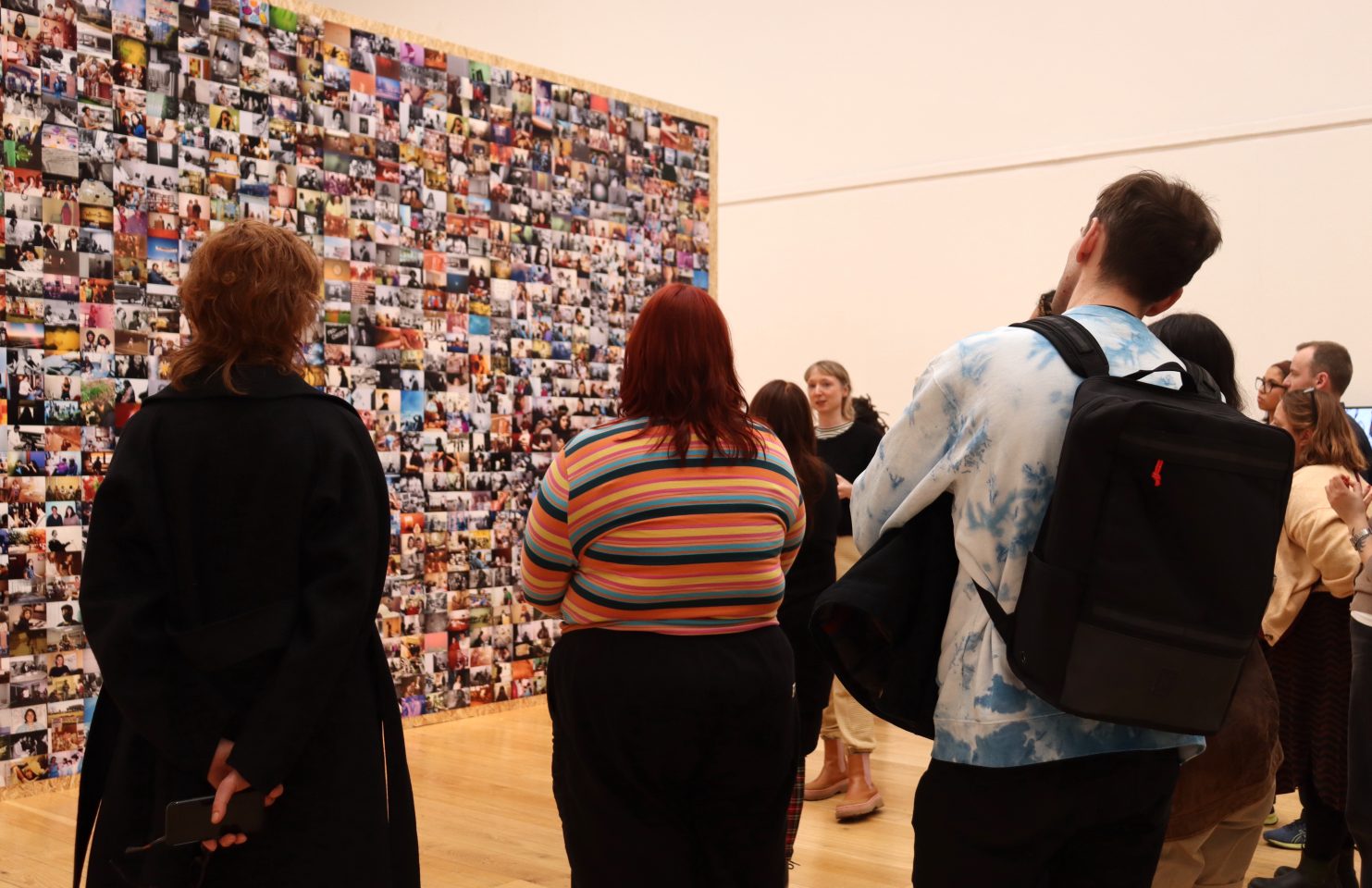 A group of adults stand in an art gallery looking at a work of art.
