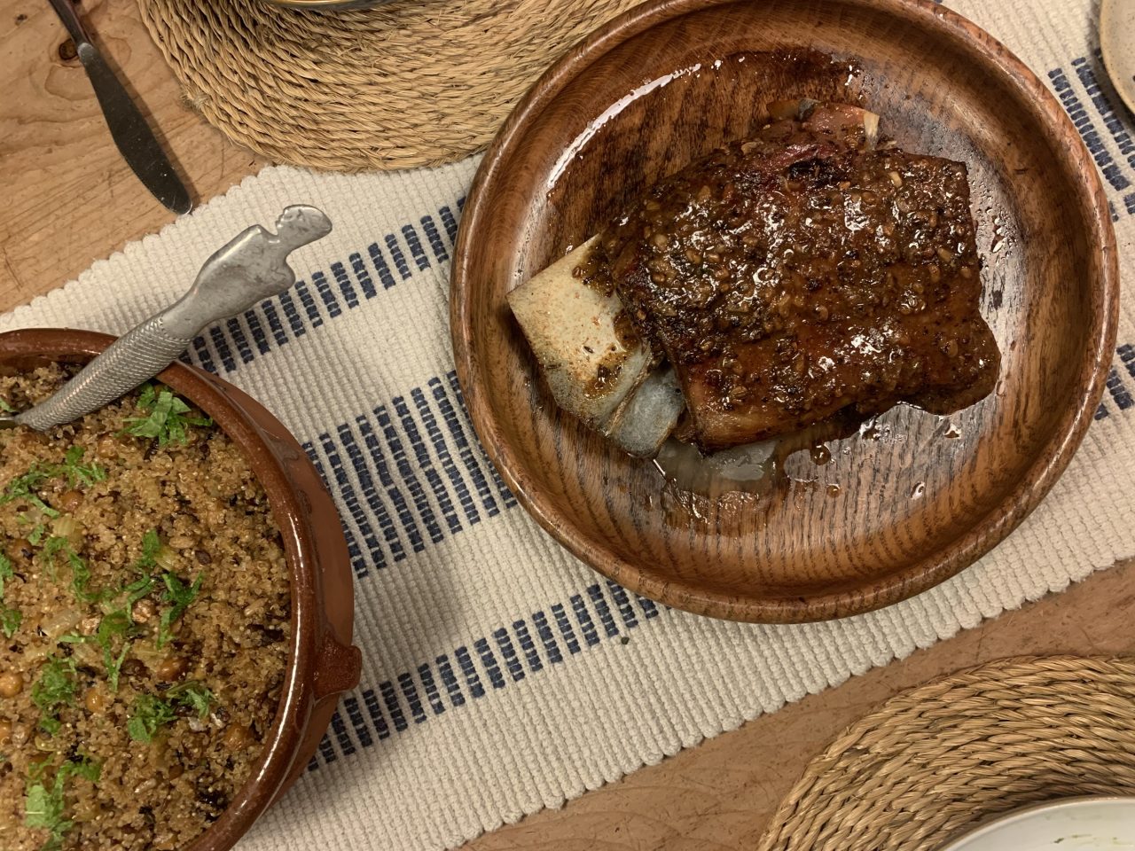 Food on plates sit on a table. The table is decorated with a linen tablecloth.
