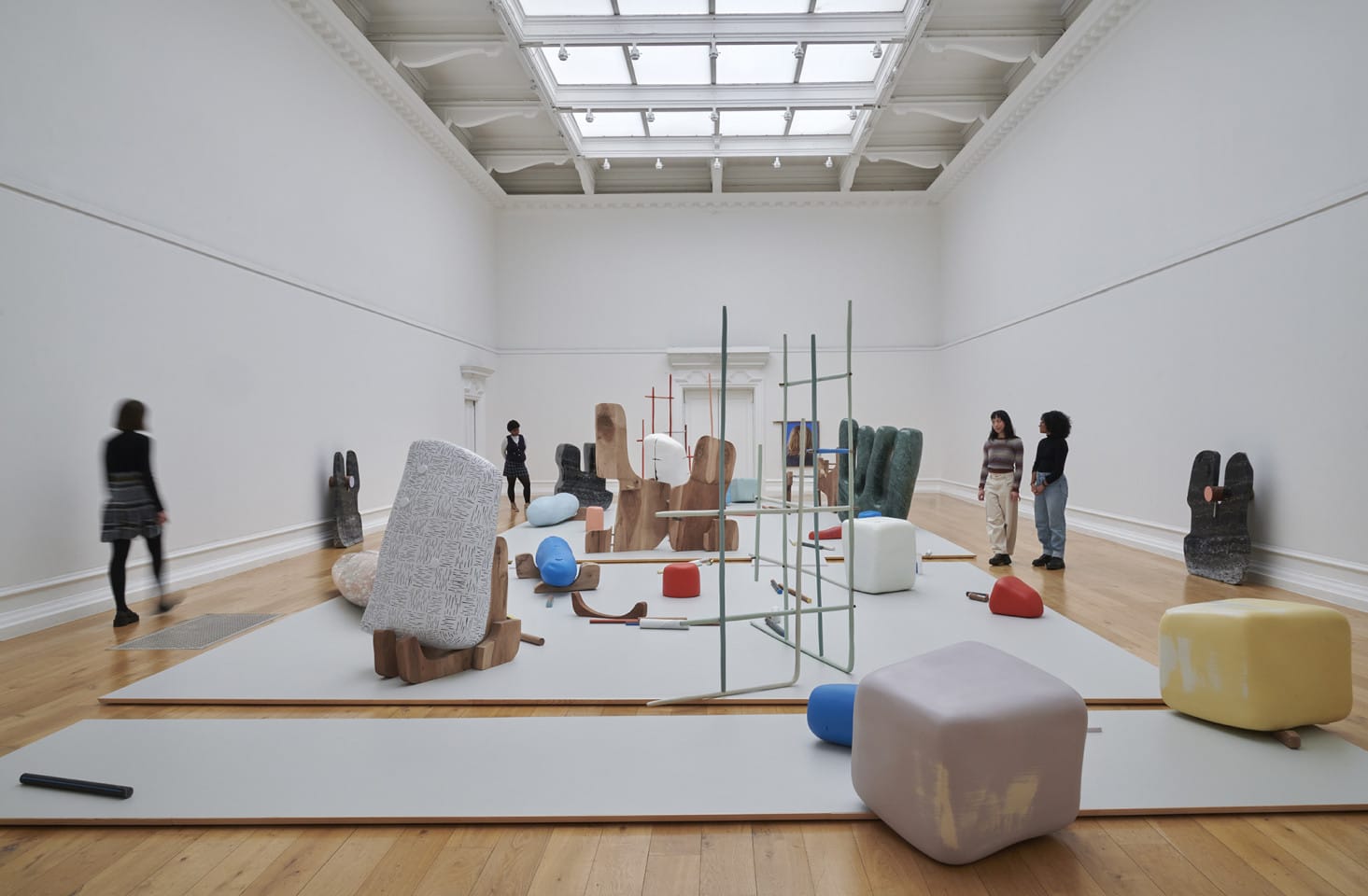 People walk around a large art gallery. They are looking at abstract sculptures and engaging with the art.