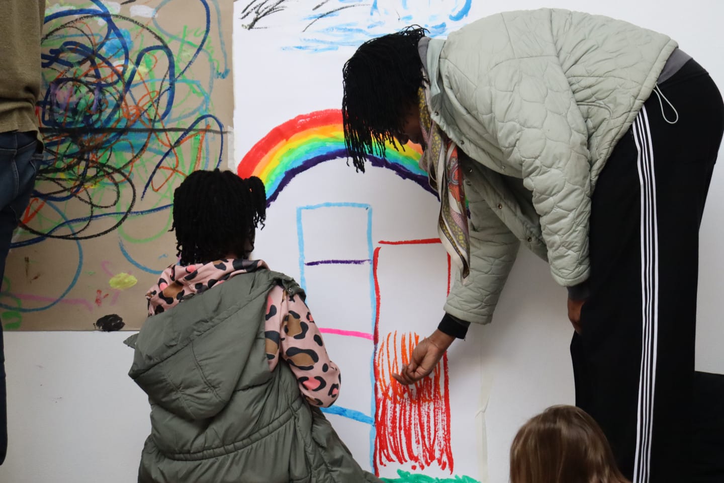 An adult and child draw on a wall together