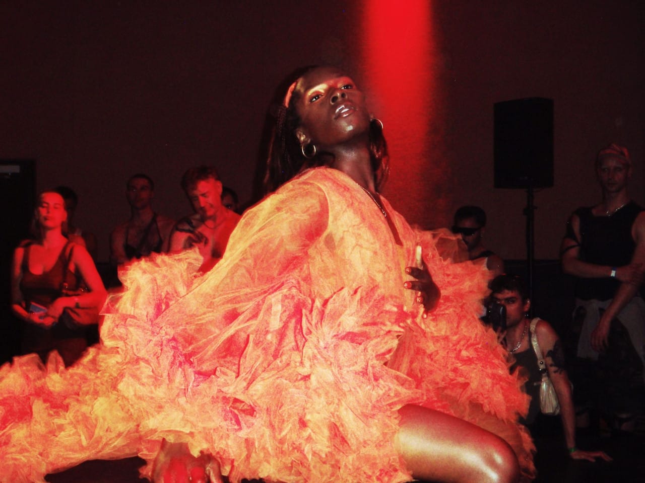 Artist Chloe Filani performs wearing a bright orange dress.
