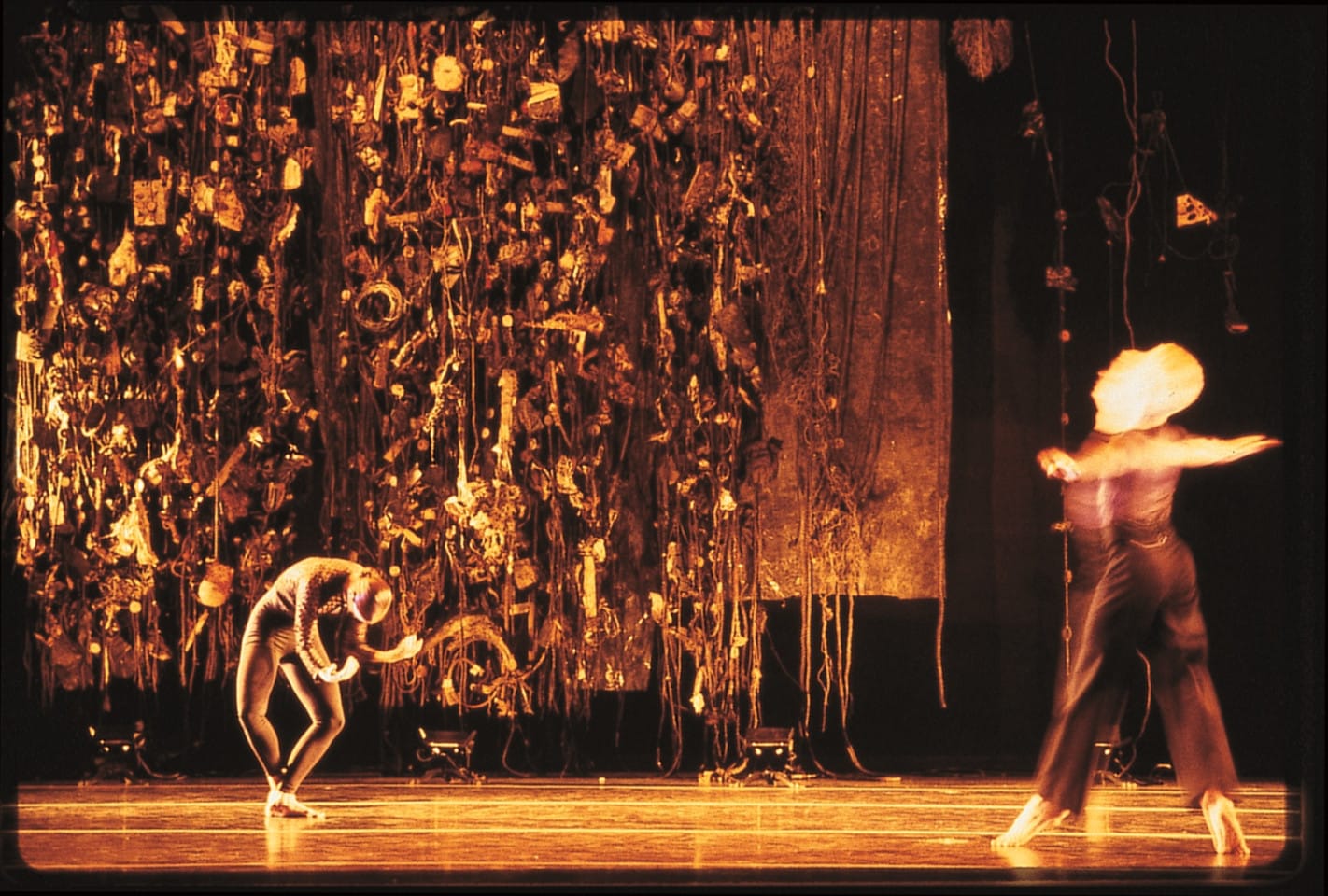 A stage performance by Merce Cunningham. Two dancers on stage in front of a backdrop designed by artist Leonardo Drew.
