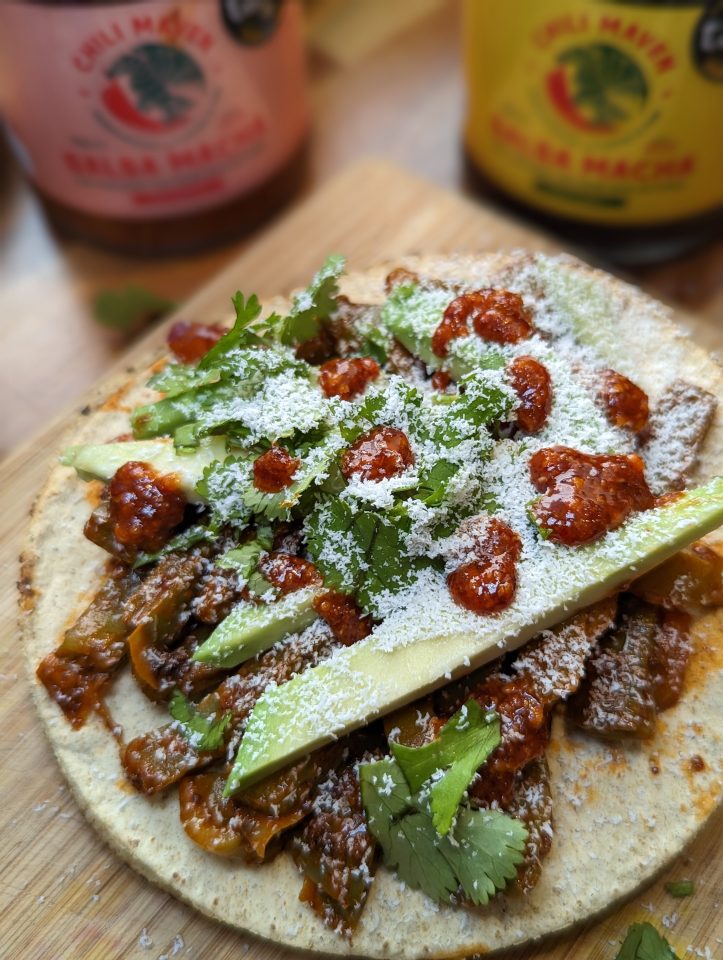 Mexican food on a table with hot sauce behind it.