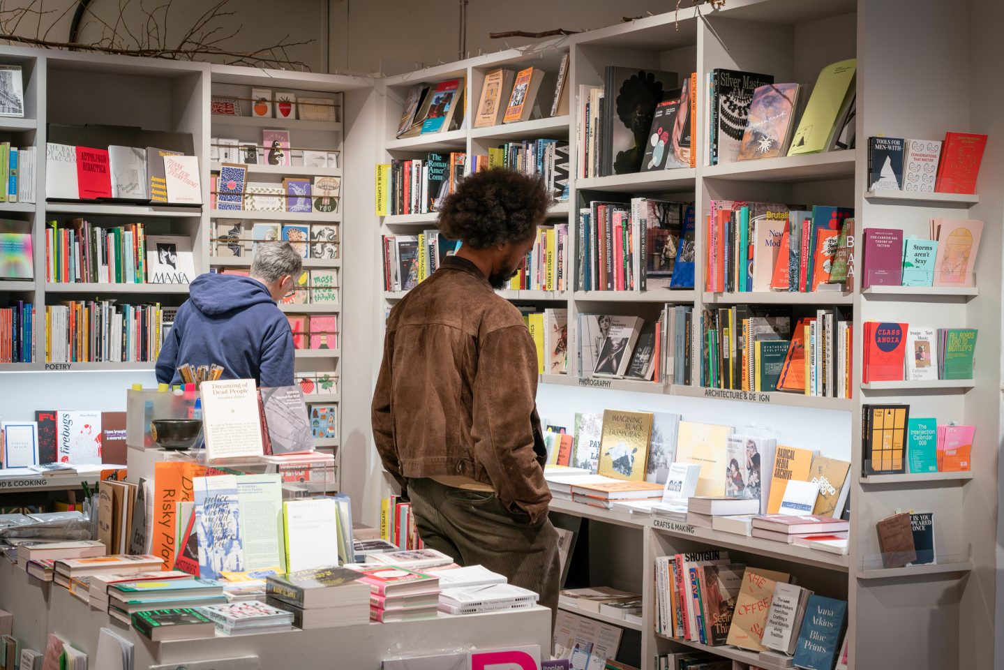 People stand in a bookshop and look at products on shelves.