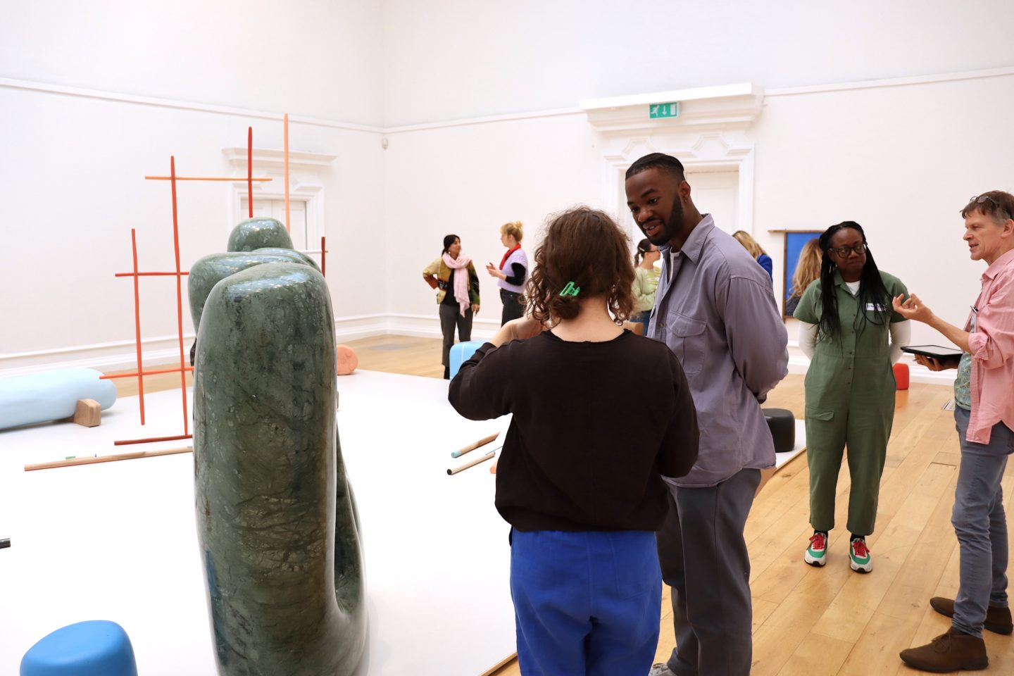 Adults in an art gallery look at art and talk to each other.