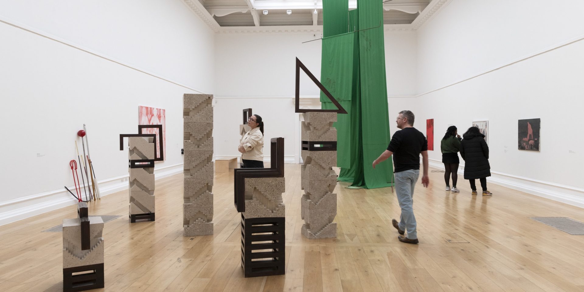 People walk around a large white art gallery looking at art.