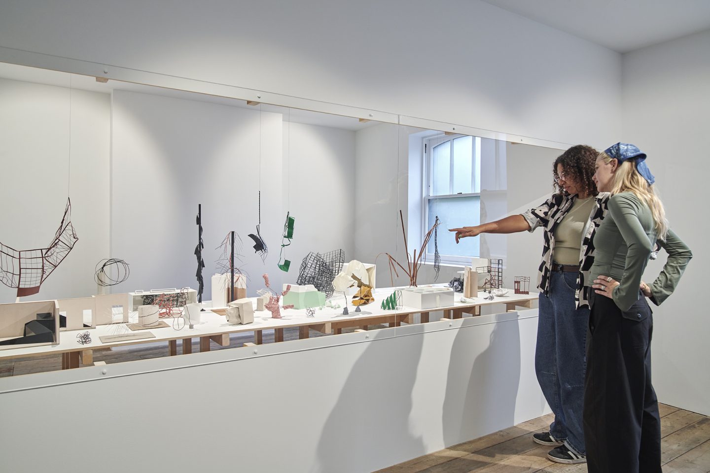 Two people look at a display of maquettes in a white room.